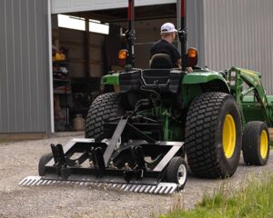 A man riding a tractor with a TR3 attached to it.