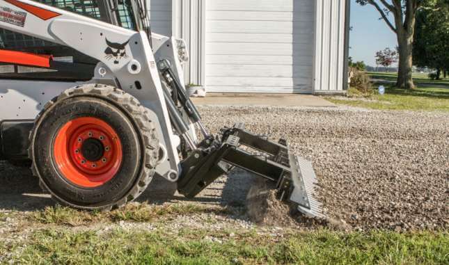 Skid loader attachment called a SR1 being used in gravel.