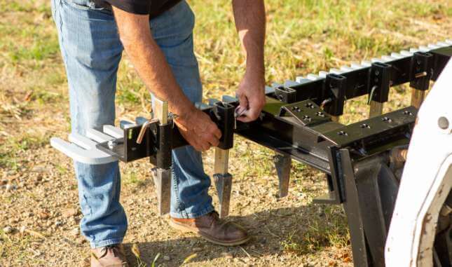 Skid steer loader attachment being displayed on grass.
