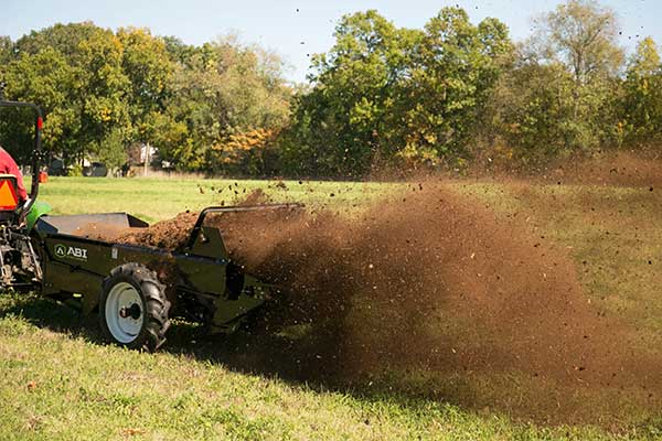 Manure spreader by ABI Attachments shredding and spreading manure.