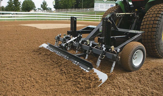 Arena drag being used and attached to a John Deere tractor.