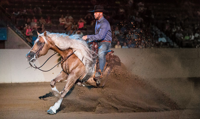 Man riding a horse in indoor arena.