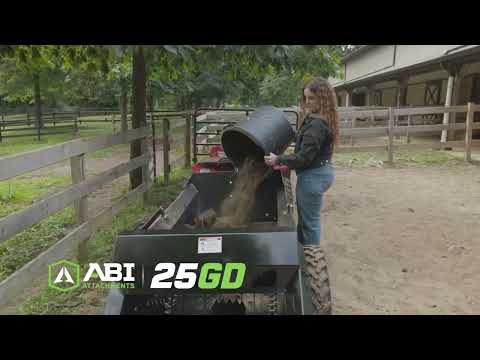 The words ‘ABI Attachments’ appear in the bottom left alongside ‘25 GO.’ A woman stands inside a stable loading manure into a manure spreader that shreds the manure.
