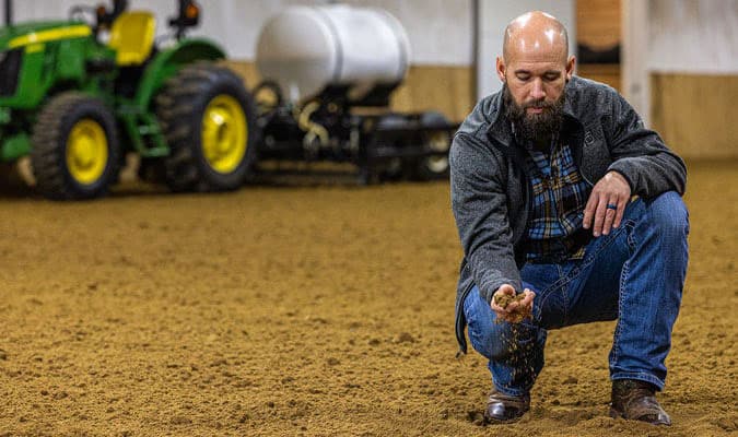 Man bending down to feel and look at the soil.