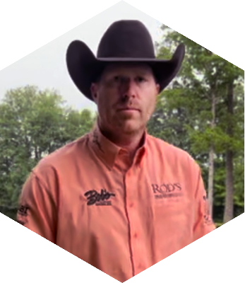 Brandon Brant in a orange collared shirt with a cowboy hat on.