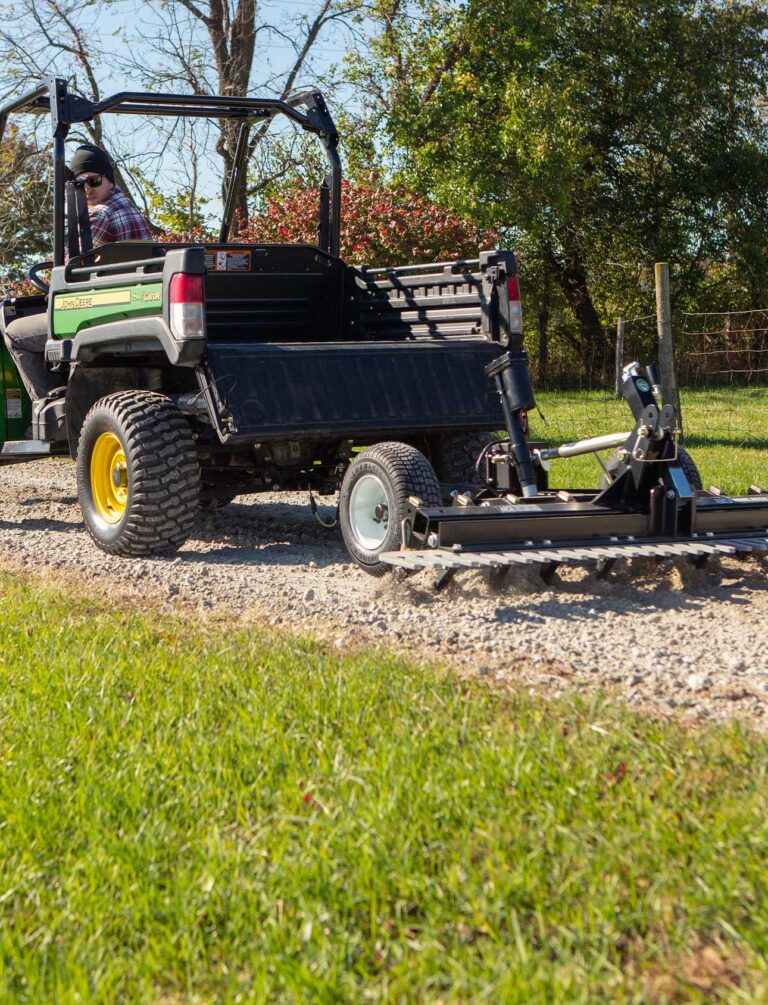 ABI Attachments' driveway grader being pulled by a ATV on gravel.