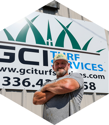 Pete Denny, owner of 'GCI Turf Services', crosses his arms looking straight onto the camera.