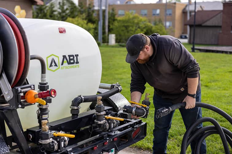 Man attaching a hose to the ABI 550 DOT Pro Water Trailer